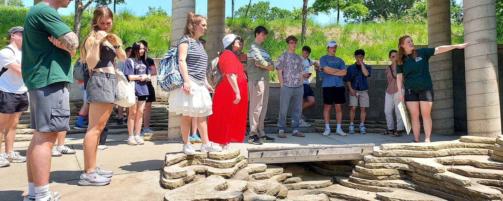 A group of students on an outdoor tour listening to a tour guide.
