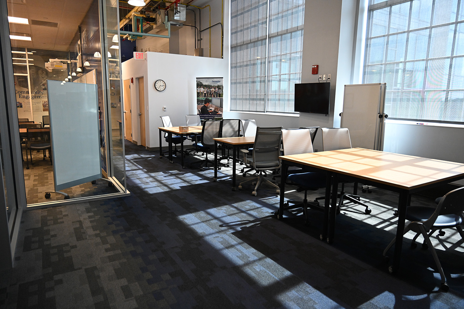 Tables and chairs line a low wall with large windows.