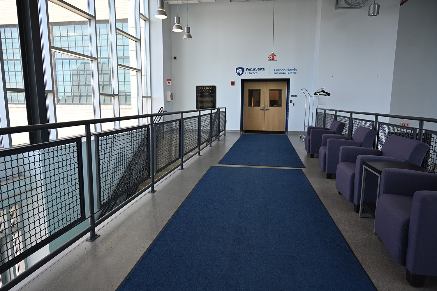 Comfortable plush chairs line an open hallway and face large windows.