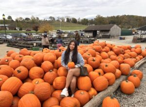 Alina siting in pile of pumpkins