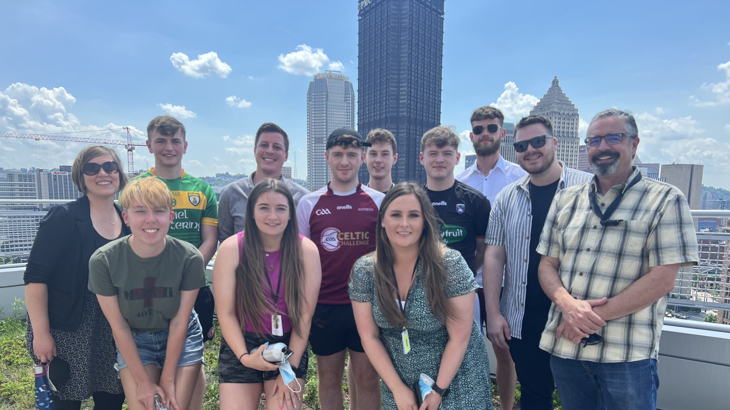 A group of students pose on the flat roof of the Energy Innovation Center - the Pittsburgh skyline is in the background