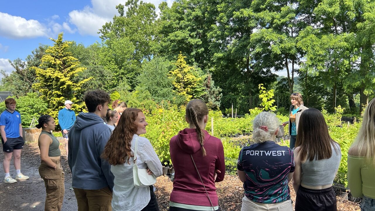Students listen to an instructor at an outdoor green space