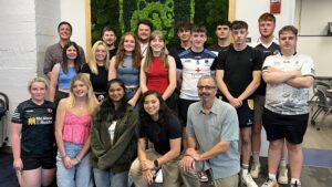 2024 High Performance Building students group pose in front of lion shield moss wall