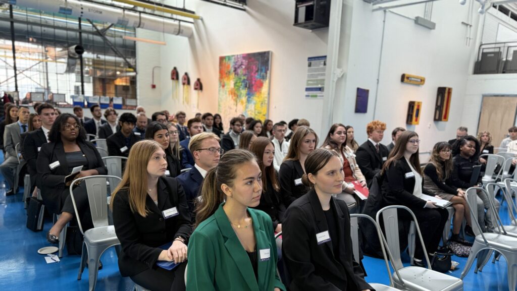 A group of students sit in a room at the Energy Innovation Center and listen to a speaker, who is not pictured.