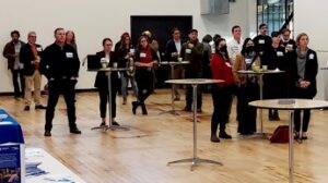 A group of people standing at high tables in a large room.