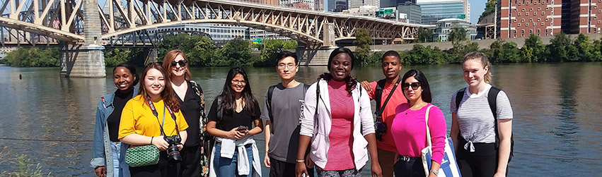 Students stand in front of a bridge in Pittsburgh