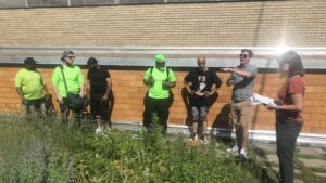 Participants in the National Green Infrastructure Certification Program stand outside a brick building and have a discussion