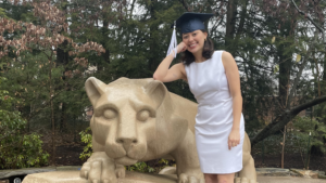 Charlotte Schmitt posing at the Nittany Lion Shrine in her graduation cap.