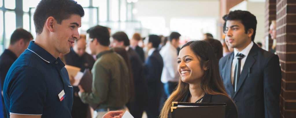 Exhibitor speaking with a student at a career fair