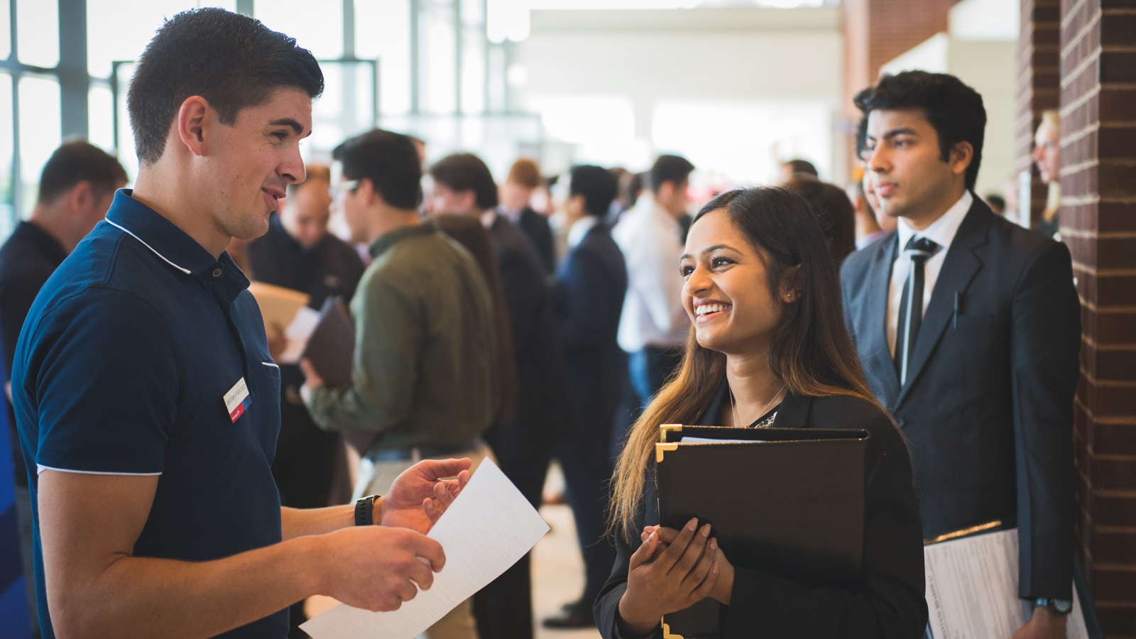 Exhibitor speaking with a student at a career fair