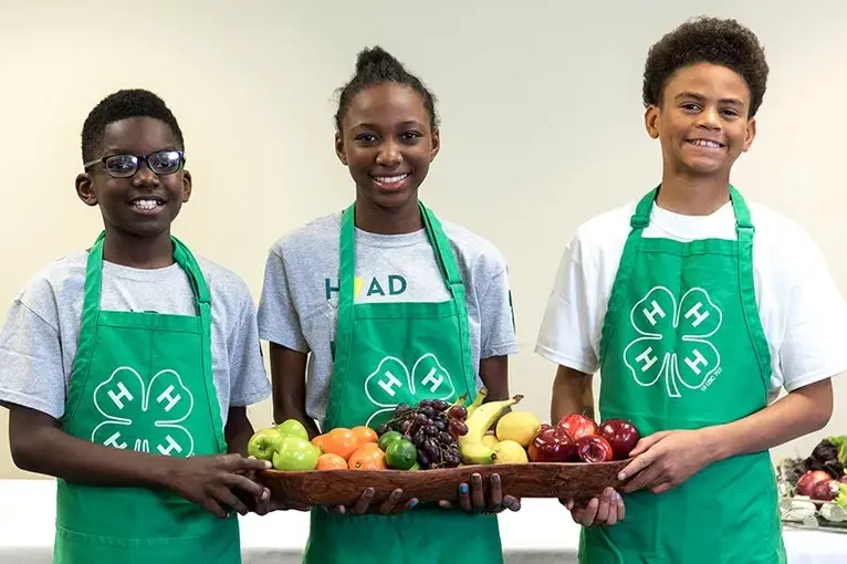 Three 4H kids holding a large plate of fruit